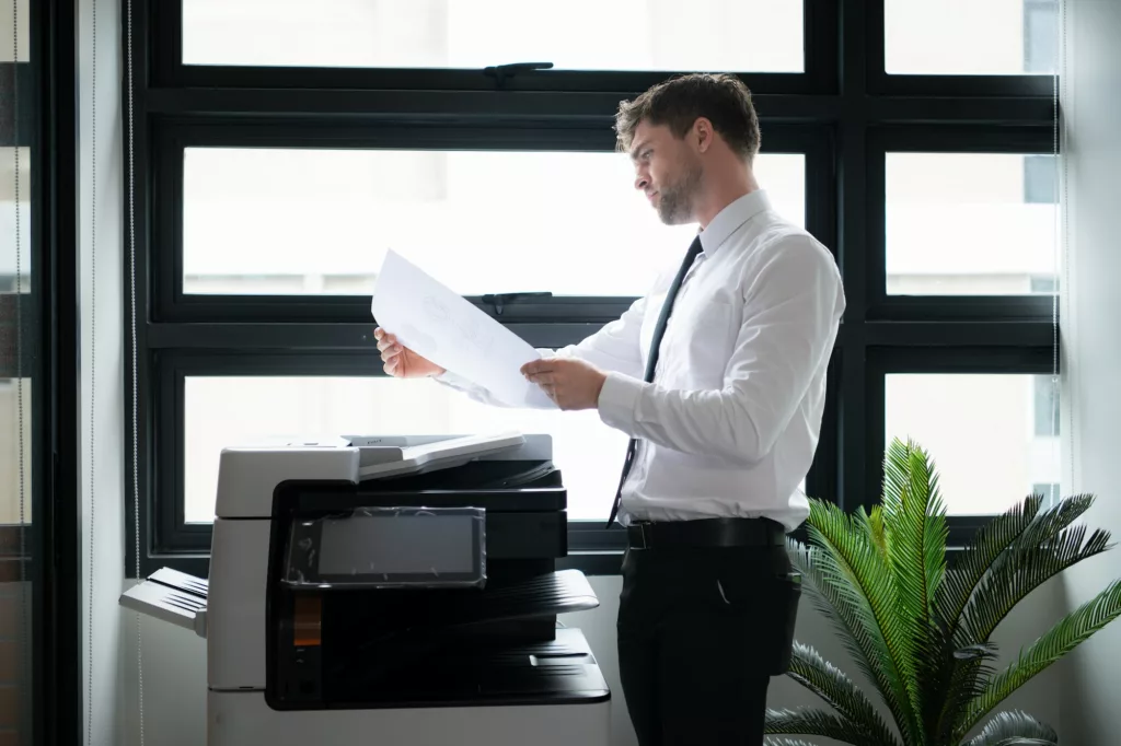 Businessman in office working with copier. Image for Office Equipment/Copiers/Printers pages of the Document Solutions section of the MCC website