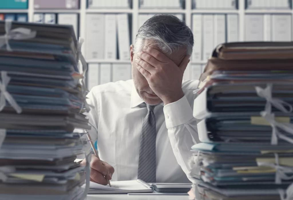 Stressed business executive and piles of paperwork